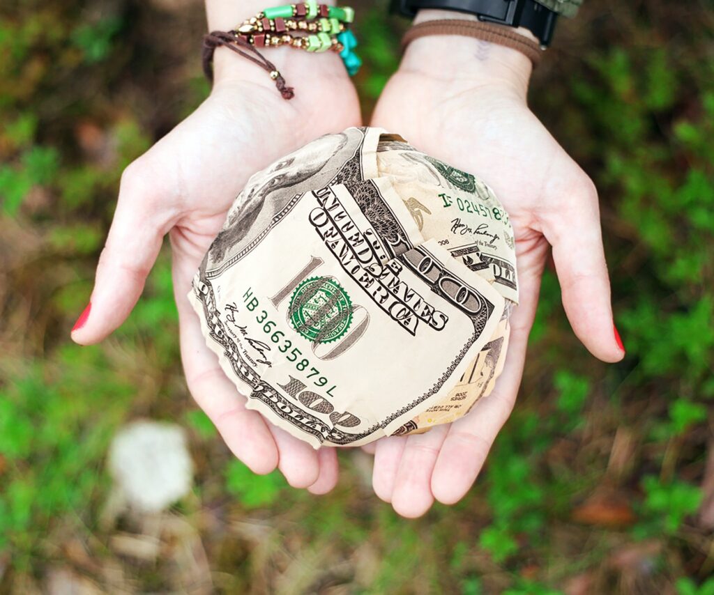 hands holding a ball made of cash