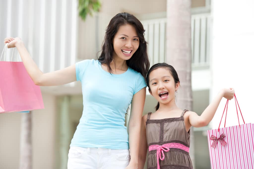 happy mother and daughter holding shopping bags