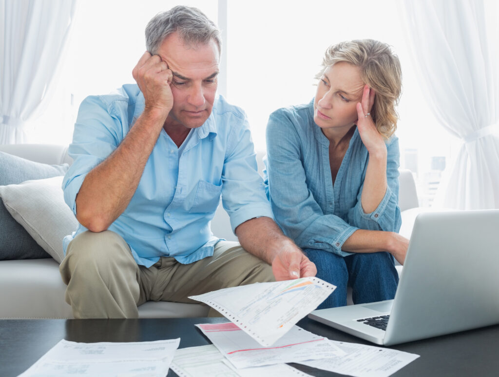 Worried couple paying bills in front of laptop