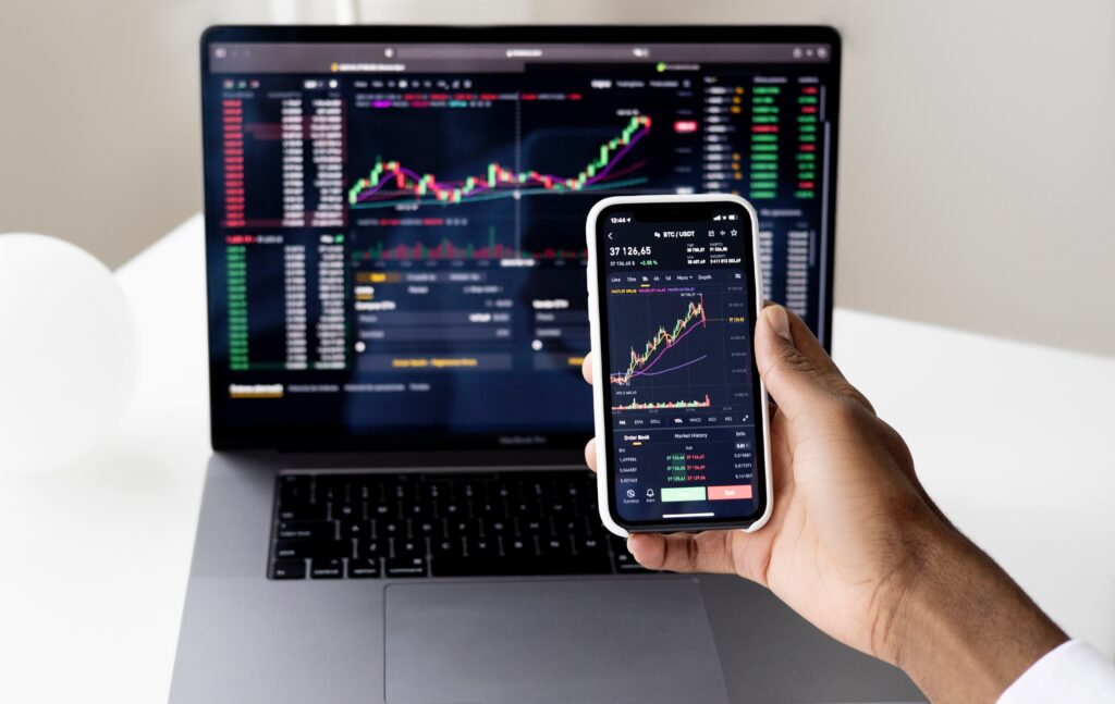 laptop and phone with stock market charts